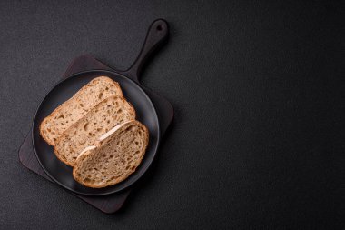 Koyu beton arka planda sandviçler için tohumlu ve tahıllı kahverengi ekmek.