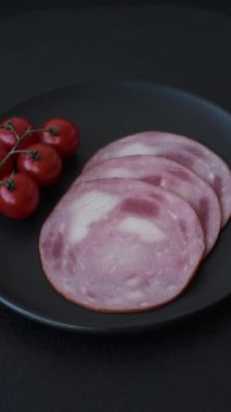 Koyu beton bir arka planda tuz ve baharatla dilimlenmiş jambon.