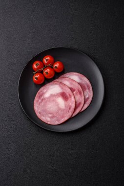 Koyu beton bir arka planda tuz ve baharatla dilimlenmiş jambon.