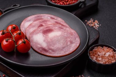 Koyu beton bir arka planda tuz ve baharatla dilimlenmiş jambon.