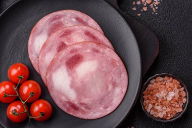 Koyu beton bir arka planda tuz ve baharatla dilimlenmiş jambon.