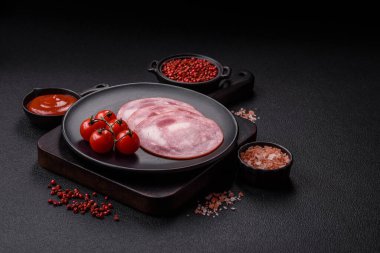 Koyu beton bir arka planda tuz ve baharatla dilimlenmiş jambon.