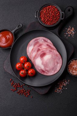 Koyu beton bir arka planda tuz ve baharatla dilimlenmiş jambon.