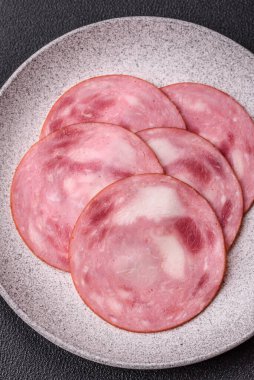 Koyu beton bir arka planda tuz ve baharatla dilimlenmiş jambon.