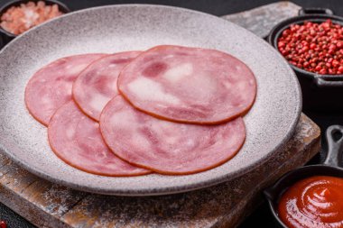 Koyu beton bir arka planda tuz ve baharatla dilimlenmiş jambon.