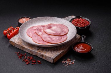 Koyu beton bir arka planda tuz ve baharatla dilimlenmiş jambon.