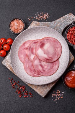 Koyu beton bir arka planda tuz ve baharatla dilimlenmiş jambon.