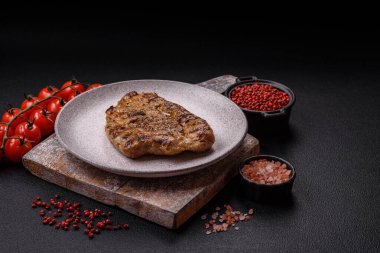 Koyu beton bir arka planda ızgara biftek veya tuzlu, baharatlı ve otlu domuz eti.