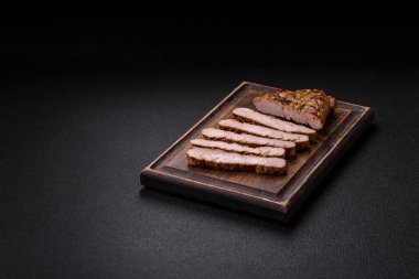 Koyu beton bir arka planda ızgara biftek veya tuzlu, baharatlı ve otlu domuz eti.