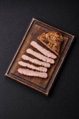 Koyu beton bir arka planda ızgara biftek veya tuzlu, baharatlı ve otlu domuz eti.