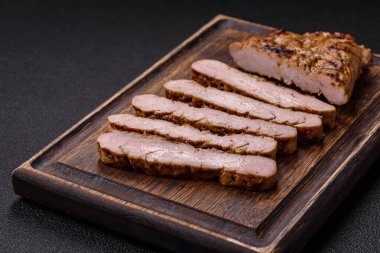 Koyu beton bir arka planda ızgara biftek veya tuzlu, baharatlı ve otlu domuz eti.