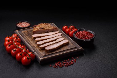 Koyu beton bir arka planda ızgara biftek veya tuzlu, baharatlı ve otlu domuz eti.