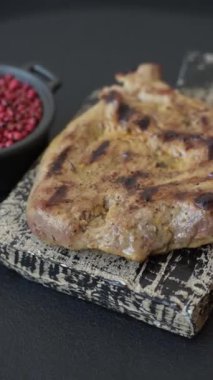 Koyu beton bir arka planda ızgara biftek veya tuzlu, baharatlı ve otlu domuz eti.