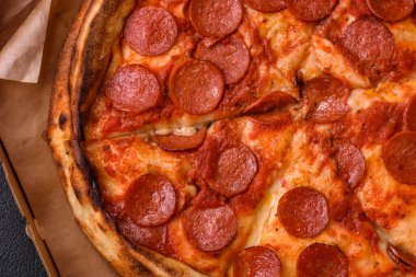 Sosisli biberli pizza, mozzarella peyniri, domates, tuz ve baharatlar koyu beton arka planda.