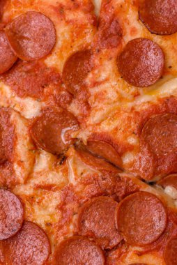 Sosisli biberli pizza, mozzarella peyniri, domates, tuz ve baharatlar koyu beton arka planda.