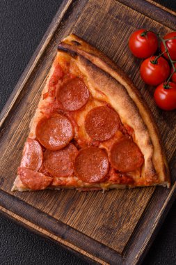 Sosisli biberli pizza, mozzarella peyniri, domates, tuz ve baharatlar koyu beton arka planda.