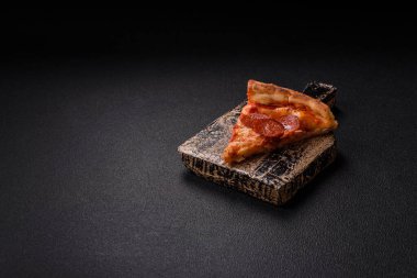 Sosisli biberli pizza, mozzarella peyniri, domates, tuz ve baharatlar koyu beton arka planda.