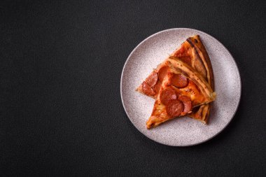 Sosisli biberli pizza, mozzarella peyniri, domates, tuz ve baharatlar koyu beton arka planda.