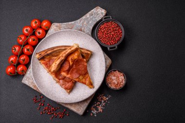 Sosisli biberli pizza, mozzarella peyniri, domates, tuz ve baharatlar koyu beton arka planda.