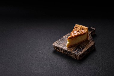 Lezzetli taze cheesecake keki ya da koyu beton arka planda seramik tabakta kremalı ve fındıklı snickers.