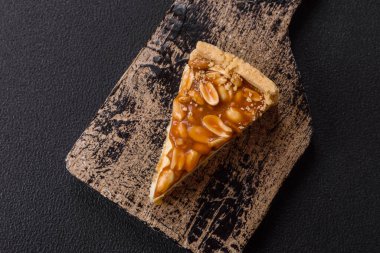 Lezzetli taze cheesecake keki ya da koyu beton arka planda seramik tabakta kremalı ve fındıklı snickers.