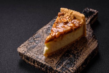 Lezzetli taze cheesecake keki ya da koyu beton arka planda seramik tabakta kremalı ve fındıklı snickers.