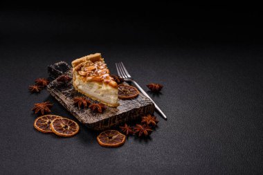 Lezzetli taze cheesecake keki ya da koyu beton arka planda seramik tabakta kremalı ve fındıklı snickers.