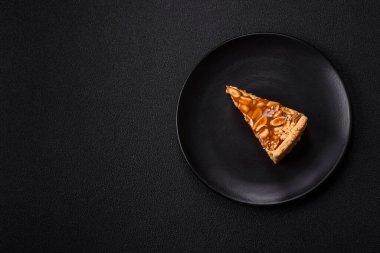 Lezzetli taze cheesecake keki ya da koyu beton arka planda seramik tabakta kremalı ve fındıklı snickers.