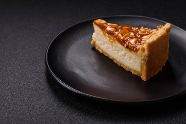 Lezzetli taze cheesecake keki ya da koyu beton arka planda seramik tabakta kremalı ve fındıklı snickers.
