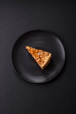 Lezzetli taze cheesecake keki ya da koyu beton arka planda seramik tabakta kremalı ve fındıklı snickers.