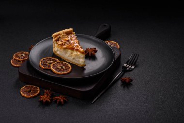 Lezzetli taze cheesecake keki ya da koyu beton arka planda seramik tabakta kremalı ve fındıklı snickers.