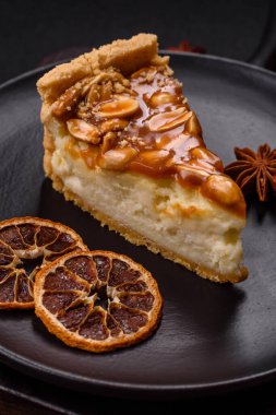 Lezzetli taze cheesecake keki ya da koyu beton arka planda seramik tabakta kremalı ve fındıklı snickers.