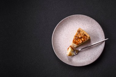 Lezzetli taze cheesecake keki ya da koyu beton arka planda seramik tabakta kremalı ve fındıklı snickers.