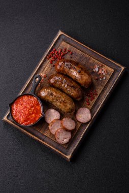 Tuzlu, baharatlı ve otlu sulu sosisler koyu beton arka planda kızartılıyor.