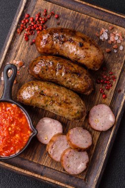 Tuzlu, baharatlı ve otlu sulu sosisler koyu beton arka planda kızartılıyor.