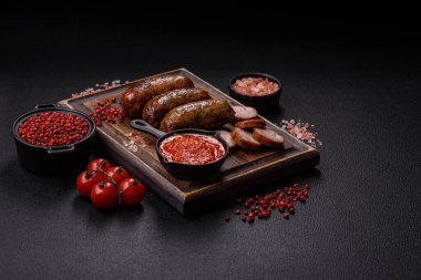 Tuzlu, baharatlı ve otlu sulu sosisler koyu beton arka planda kızartılıyor.