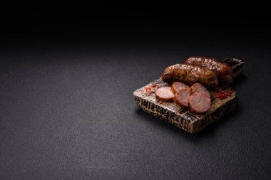 Tuzlu, baharatlı ve otlu sulu sosisler koyu beton arka planda kızartılıyor.