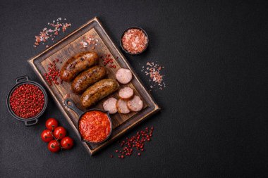 Tuzlu, baharatlı ve otlu sulu sosisler koyu beton arka planda kızartılıyor.