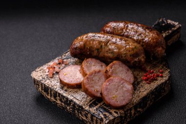 Tuzlu, baharatlı ve otlu sulu sosisler koyu beton arka planda kızartılıyor.