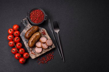 Tuzlu, baharatlı ve otlu sulu sosisler koyu beton arka planda kızartılıyor.