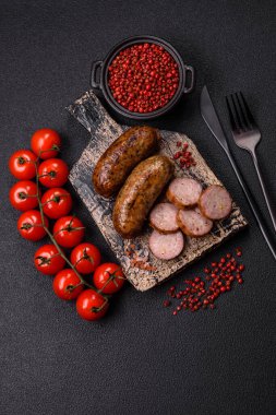 Tuzlu, baharatlı ve otlu sulu sosisler koyu beton arka planda kızartılıyor.