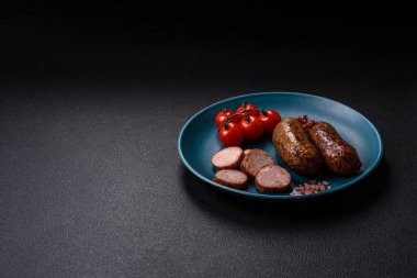 Tuzlu, baharatlı ve otlu sulu sosisler koyu beton arka planda kızartılıyor.