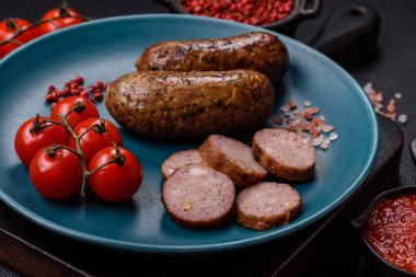 Tuzlu, baharatlı ve otlu sulu sosisler koyu beton arka planda kızartılıyor.