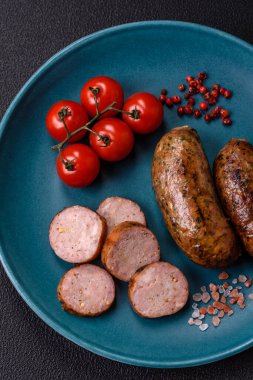 Tuzlu, baharatlı ve otlu sulu sosisler koyu beton arka planda kızartılıyor.