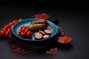 Tuzlu, baharatlı ve otlu sulu sosisler koyu beton arka planda kızartılıyor.