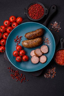 Tuzlu, baharatlı ve otlu sulu sosisler koyu beton arka planda kızartılıyor.