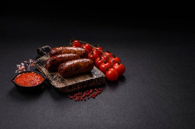 Tuzlu, baharatlı ve otlu sulu sosisler koyu beton arka planda kızartılıyor.