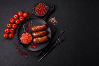 Tuzlu, baharatlı ve otlu sulu sosisler koyu beton arka planda kızartılıyor.