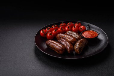 Tuzlu, baharatlı ve otlu sulu sosisler koyu beton arka planda kızartılıyor.