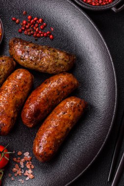 Tuzlu, baharatlı ve otlu sulu sosisler koyu beton arka planda kızartılıyor.
